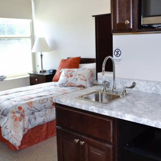 A cozy bedroom with a kitchenette and single bed.