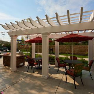 Outdoor patio area with a pergola, tables, and chairs under umbrellas.