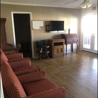A cozy living room featuring a series of red chairs, a wall-mounted television, and a wooden floor.