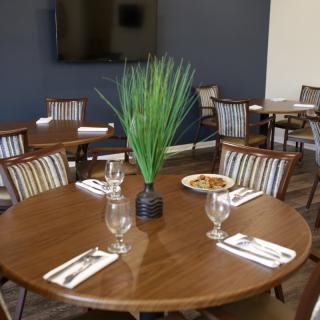 A neatly set dining table in a restaurant with glassware, cutlery, and a plant centerpiece.