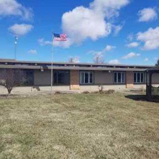 A school building with an American flag flying under a partly cloudy sky.