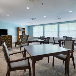 A bright and spacious room with tables and chairs arranged in a communal setting.