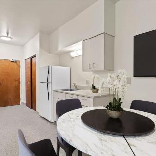 A modern kitchen and dining area featuring a white refrigerator, marble table, and elegant decor.