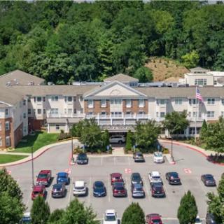 Aerial view of a residential apartment complex with a spacious parking lot surrounded by greenery.