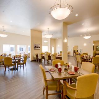 A spacious and modern dining area with neatly arranged tables and chairs, featuring warm lighting.