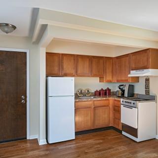 A compact kitchen in an apartment with wooden cabinets, a white refrigerator, and a stove.