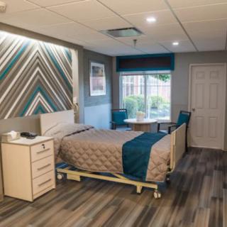 A modern hospital room with a single bed, nightstand, and contemporary decor.