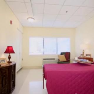 A cozy bedroom with a red bedspread and a bedside lamp.