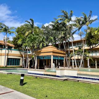 A picturesque resort with tropical architecture, surrounded by lush greenery and palm trees.