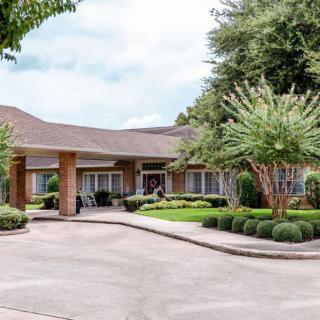 A suburban house with a well-maintained driveway and surrounding greenery.