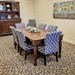 A dining room setup with a wooden table, patterned chairs, and a decorative carpet.