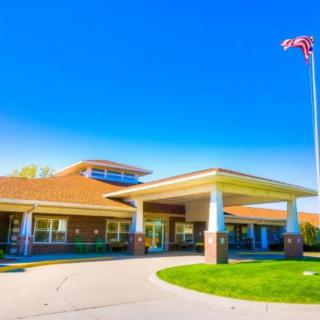 A modern building entrance with an American flag waving against a clear blue sky.