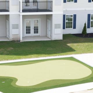 A residential building with a small putting green in the front yard.