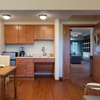 A modern kitchen featuring wooden cabinets, a dining area, and contemporary appliances.