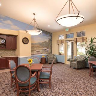 A cozy lounge area with tables, chairs, and comfortable seating, featuring a decorative mural and elegant lighting.