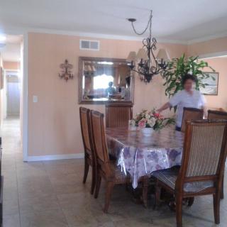 A dining room with a table set and a chandelier, featuring chairs, a mirror, and an indoor plant.