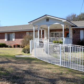 A single-story brick house with a white accessibility ramp leading to the entrance.