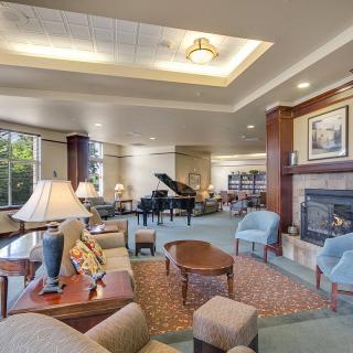 A spacious and elegantly designed living room featuring comfortable seating, a grand piano, and a cozy fireplace.