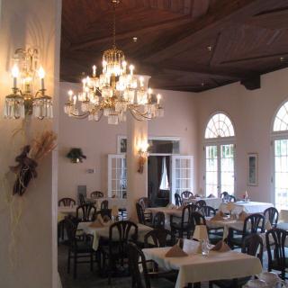 An elegant dining area featuring chandeliers and neatly arranged tables and chairs.
