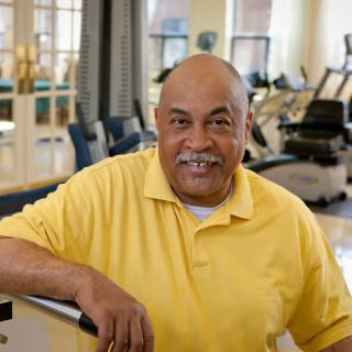 A cheerful senior man in a yellow shirt, enjoying his time at the gym.