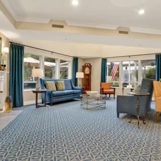 A spacious and well-lit living room with sofas, chairs, and large windows offering a cozy and inviting atmosphere.
