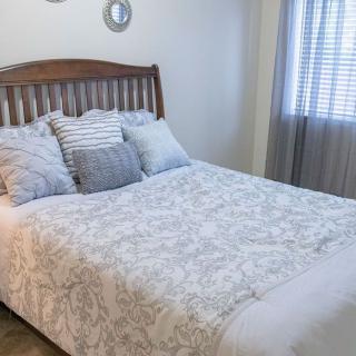 A cozy bedroom with a neatly made bed, decorated with multiple pillows and a patterned comforter.