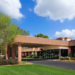 A modern brick building under a blue sky with scattered clouds, featuring a well-maintained lawn and driveway.