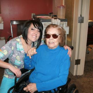 A joyful moment shared between a young caregiver and an elderly woman in a wheelchair.