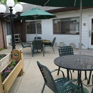 A cozy outdoor patio area with tables, chairs, umbrellas, and a planter.