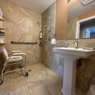 A well-equipped accessible bathroom featuring a sink, mobility aid, and safety features.