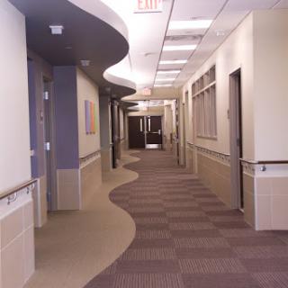 A well-lit and clean hospital hallway with a curved design.