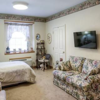 A cozy bedroom with floral furniture and a television.