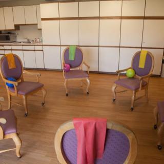 A fitness room setup with chairs, colorful towels, and yoga balls ready for a class.