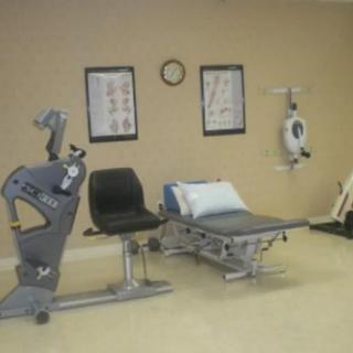 A physical therapy room with exercise equipment and a therapy bed.
