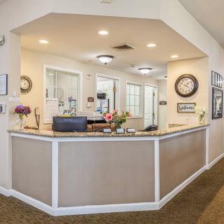 A welcoming reception area with a desk, flowers, and modern lighting.