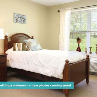 A cozy bedroom with a wooden bed and a large window letting in natural light.