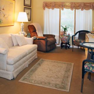 A cozy living room with a white sofa, armchair, rug, and decorative elements.