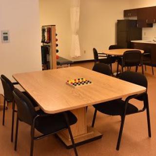 A cozy kitchen area with tables and chairs, featuring a chessboard centerpiece.