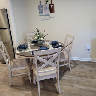A cozy dining area featuring a round table set with blue napkins and elegant dinnerware.