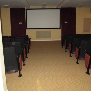 An empty movie theater with rows of seats facing a large screen.