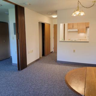 An empty apartment interior with an open kitchen and dining area.