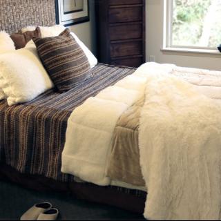 A cozy bedroom with a neatly made bed, featuring striped pillows and a soft blanket.