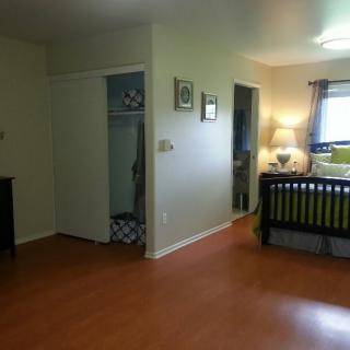 A spacious bedroom with a crib, hardwood flooring, and ample natural light.