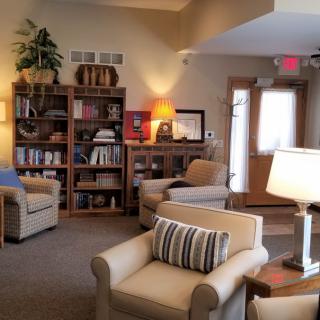 A cozy living room with comfortable armchairs, bookshelves, and warm lighting.