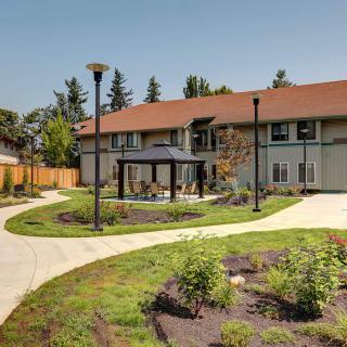 A modern building with a landscaped garden and winding pathways under clear skies.