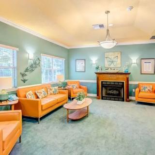 A cozy living room with orange furniture, green walls, and a central fireplace.