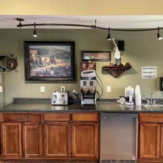 A cozy kitchen corner with a coffee station, featuring appliances, wooden cabinets, and decorative artwork.