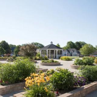 A beautiful garden with vibrant flowers and a central pavilion under a clear blue sky.