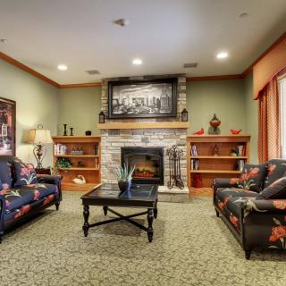 A cozy living room featuring a central fireplace, surrounded by comfortable furniture and bookshelves.