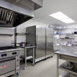 A clean and modern commercial kitchen with stainless steel appliances and ample preparation space.